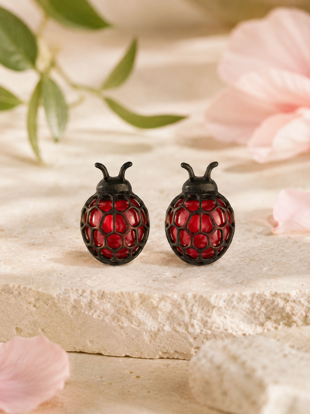 Detalle frontal de pendientes Abstract Ladybug sobre piedra clara con petalos